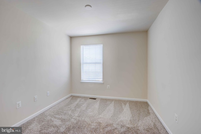spare room featuring carpet flooring and baseboards