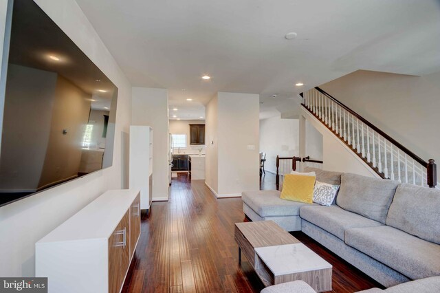 living room with dark wood finished floors, recessed lighting, and stairway