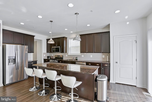 kitchen with backsplash, dark brown cabinetry, a kitchen island, and stainless steel appliances