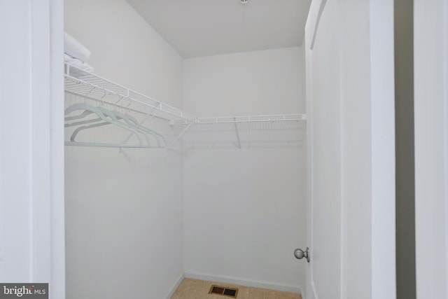 walk in closet featuring visible vents and light colored carpet
