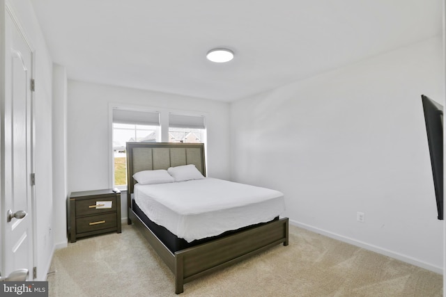 bedroom with baseboards and light colored carpet