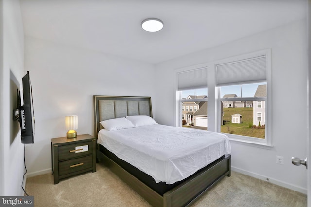bedroom featuring light colored carpet and baseboards