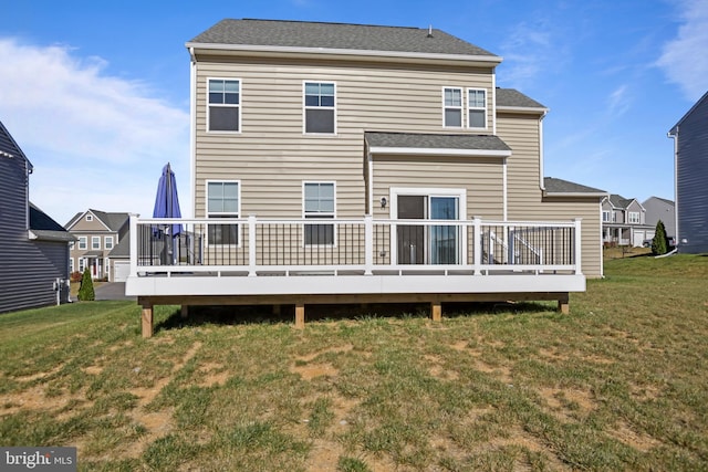 rear view of house featuring roof with shingles, a yard, and a deck