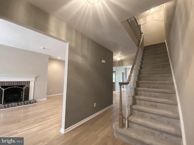 staircase with baseboards, wood finished floors, and a fireplace