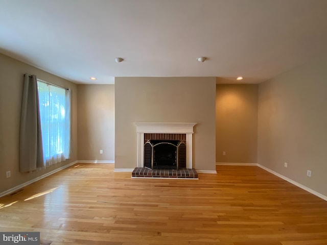 unfurnished living room featuring light wood-type flooring, recessed lighting, baseboards, and a brick fireplace