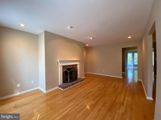 unfurnished living room featuring a brick fireplace, recessed lighting, baseboards, and light wood finished floors
