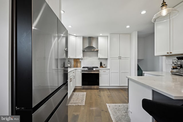 48 Evergreen Ln, Burlington, NJ 08016 - kitchen with wood finished floors, stainless steel gas stove, refrigerator, wall chimney exhaust hood, and white cabinets