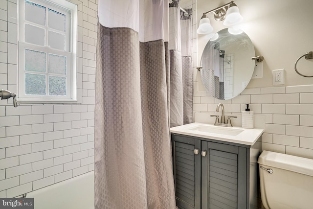 bathroom with vanity, toilet, and tile walls