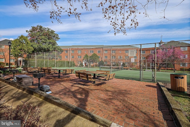 view of property's community with a gate, fence, and a tennis court