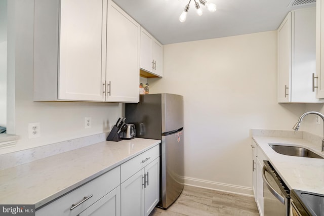 kitchen with stainless steel appliances, white cabinetry, a sink, and light wood-type flooring