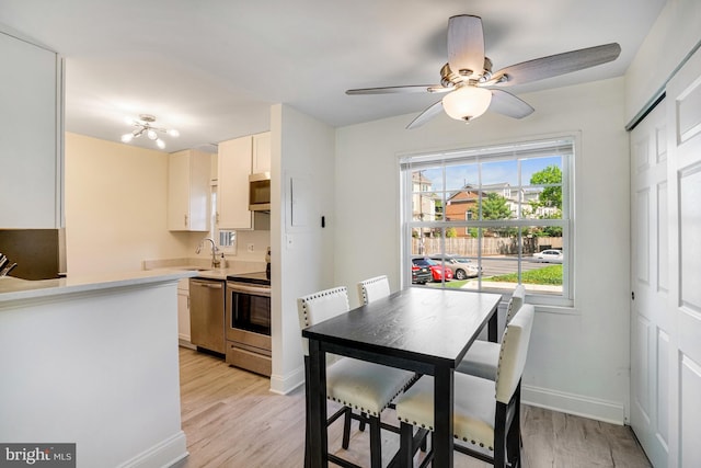 kitchen featuring light countertops, appliances with stainless steel finishes, baseboards, and light wood finished floors