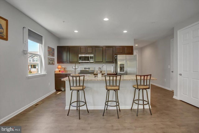 kitchen with a kitchen breakfast bar, stainless steel appliances, recessed lighting, and wood finished floors