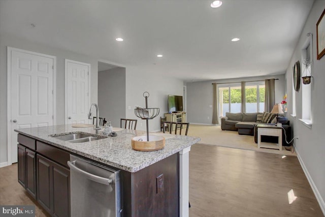 kitchen with a sink, light wood-style floors, dishwasher, baseboards, and open floor plan