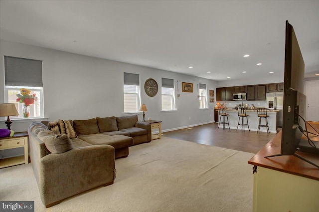 living room featuring baseboards, recessed lighting, and light colored carpet
