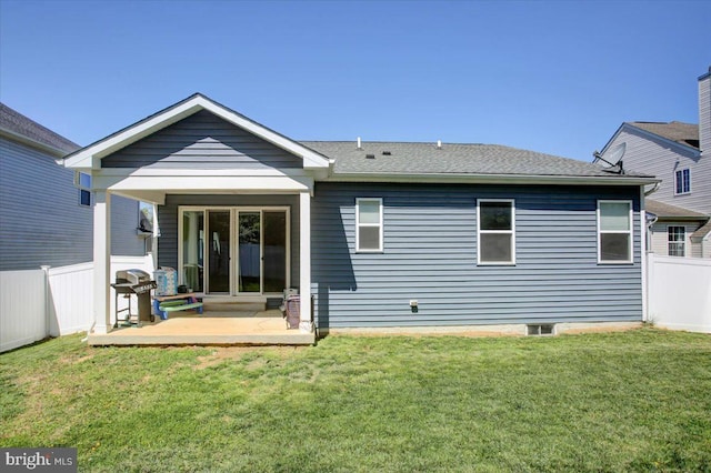 rear view of house with fence and a yard