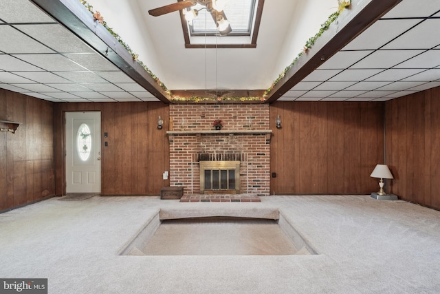 unfurnished living room with carpet flooring, wooden walls, and ceiling fan