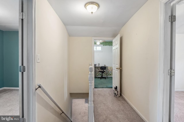 corridor featuring carpet flooring, baseboards, and an upstairs landing