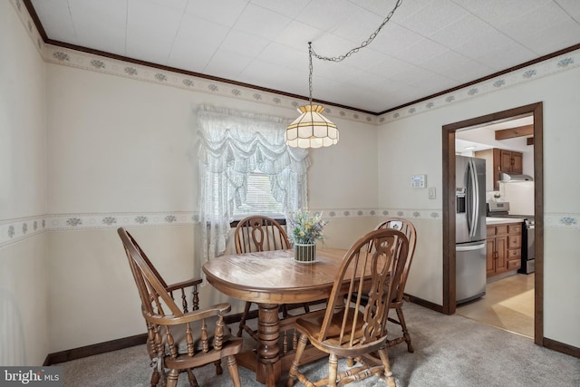 dining room with crown molding and light carpet