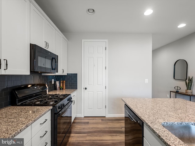 kitchen with backsplash, dark wood-style flooring, light stone countertops, black appliances, and white cabinetry