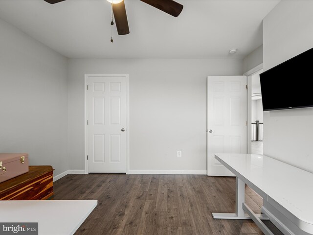 unfurnished office with baseboards, dark wood-style flooring, and ceiling fan