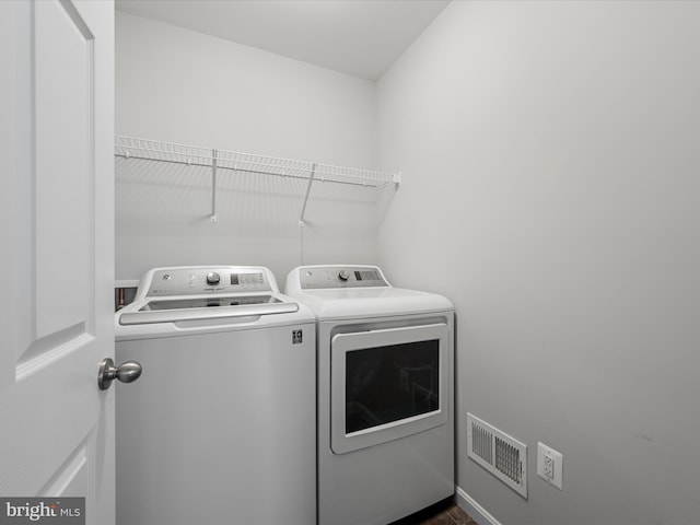 clothes washing area featuring laundry area, visible vents, and washer and clothes dryer
