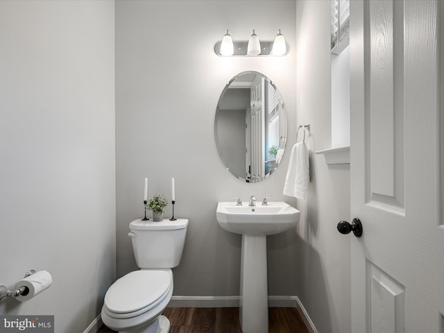 half bathroom featuring toilet, baseboards, and wood finished floors
