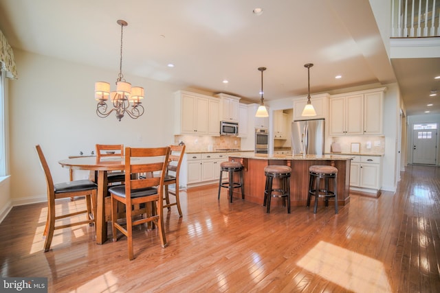 dining area featuring an inviting chandelier, baseboards, recessed lighting, and light wood-style flooring