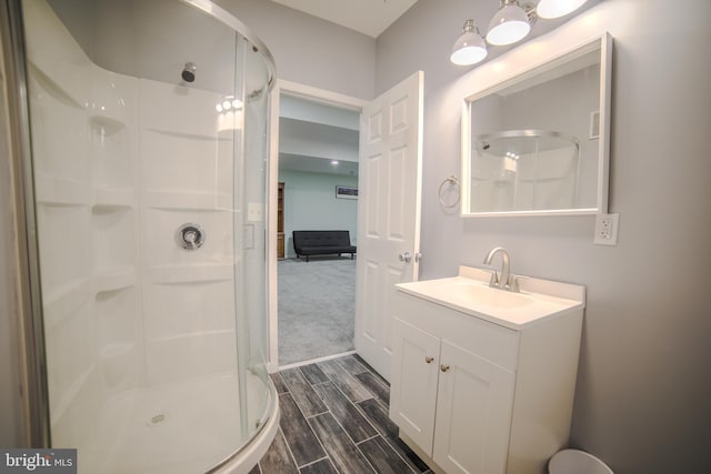 full bath with vanity, a stall shower, and wood finished floors