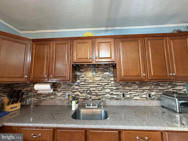 kitchen featuring brown cabinetry, tasteful backsplash, a sink, a toaster, and ornamental molding