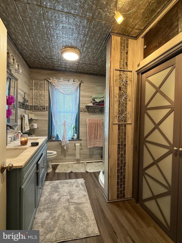 bathroom with an ornate ceiling, toilet, wood finished floors, and vanity