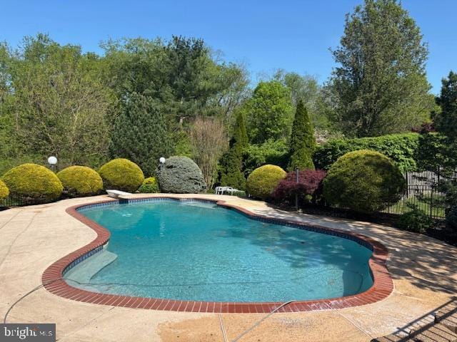 outdoor pool featuring a diving board, a patio area, and fence