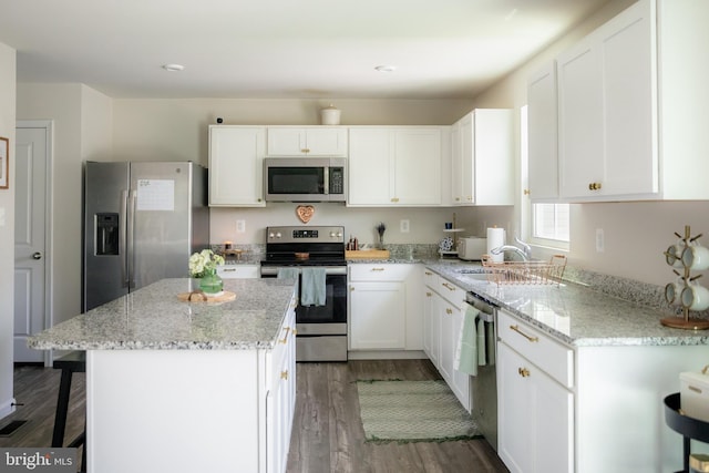300 Coville St, Middletown, VA 22645 - kitchen with wood finished floors, white cabinetry, light stone counters, a sink, and appliances with stainless steel finishes