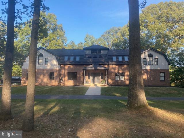back of property with a lawn and brick siding