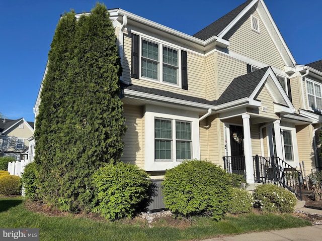 traditional-style house with central AC and a shingled roof