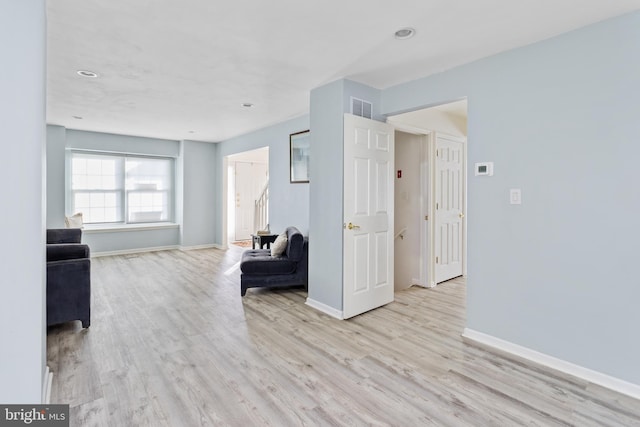 unfurnished living room featuring visible vents, baseboards, and wood finished floors