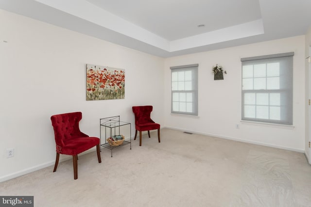 sitting room featuring carpet flooring, a tray ceiling, visible vents, and baseboards