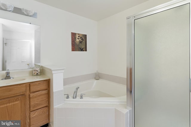 bathroom with a stall shower, a bath, and vanity