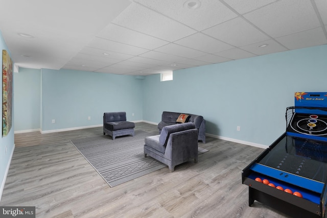 living area with baseboards, wood finished floors, and a paneled ceiling