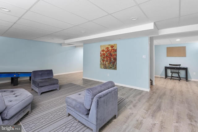 living room with baseboards, a paneled ceiling, and wood finished floors