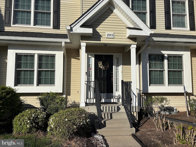 view of exterior entry featuring a shingled roof
