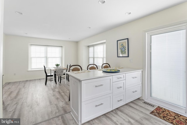 kitchen featuring visible vents, light wood-style floors, plenty of natural light, and white cabinetry