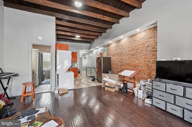 living room featuring baseboards, brick wall, beam ceiling, and light wood-type flooring