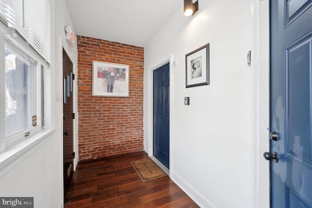corridor with dark wood-style flooring and brick wall