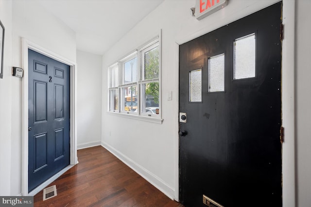 entryway with baseboards, visible vents, and dark wood-type flooring