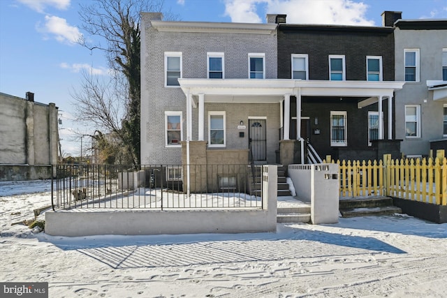townhome / multi-family property featuring brick siding and a fenced front yard