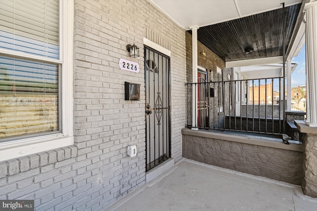 property entrance featuring a porch and brick siding
