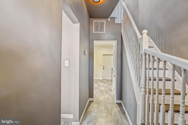 corridor with baseboards, stairs, and visible vents