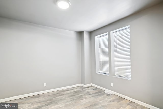 spare room featuring baseboards and wood finished floors