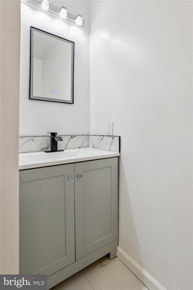 bathroom featuring baseboards, marble finish floor, and vanity
