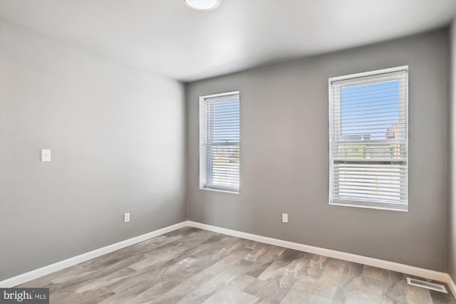 empty room with baseboards, wood finished floors, and visible vents